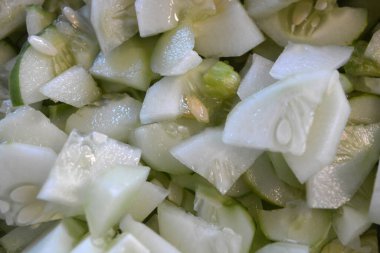 Bir sürü dilimlenmiş çeyrek salatalık büyük beyaz bir salata kasesine istiflenmiş. Faydalı sebzeler, sağlıklı yiyecekler, dilimlenmiş tohumlu salatalıklar..