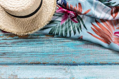Açık mavi ahşap arka planda mavi eşarplı hasır şapka, plaj ve yaz konsepti.
