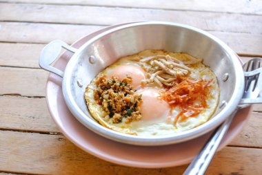 Tavada pişmiş yumurta ve ahşap masada malzemeler..