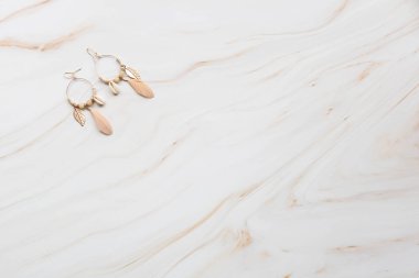 Fotokopi alanı olan mermer bir arka planda bir çift küpe.