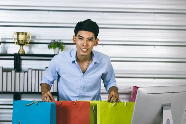 A young Asian influence male vlogger is holding shopping bags.