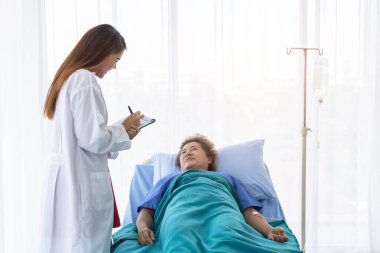 Genç ve güzel bir doktor yaşlı bir kadını muayene ediyor..