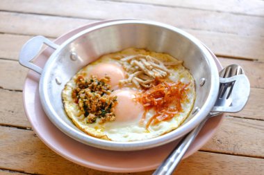 Tavada pişmiş yumurta ve ahşap masada malzemeler..