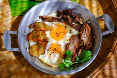 Tavada pişmiş yumurta ve ahşap masada malzemeler..