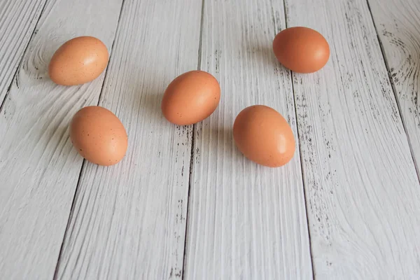 Brown chicken eggs lay on the wooden floor.