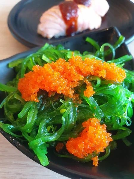 Japanese food in set different types of sushi with seaweed salad and gari (ginger) is a healthy food at the upper right of the serving board in japan restaurant