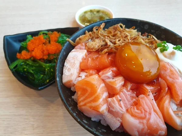 Japon yemeği saşimi somonu ve farklı türde suşi ve deniz yosunu salatası ve gari (zencefil) Japon restoranındaki servis panosunun sağ üst kısmında sağlıklı bir yemektir.