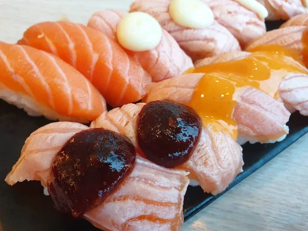 Japon yemeği saşimi somonu ve farklı türde suşi ve deniz yosunu salatası ve gari (zencefil) Japon restoranındaki servis panosunun sağ üst kısmında sağlıklı bir yemektir.