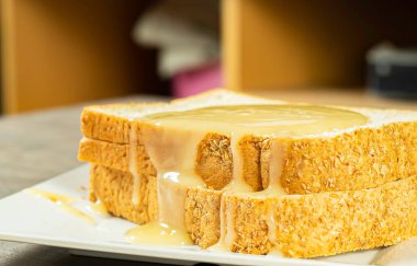 Yakın plan seçilmiş bir odak ekmeği üzerine beyaz ve kaşık paslanmaz yemek üzerine yoğunlaştırılmış süt ve sağlık arka planı için içecek.