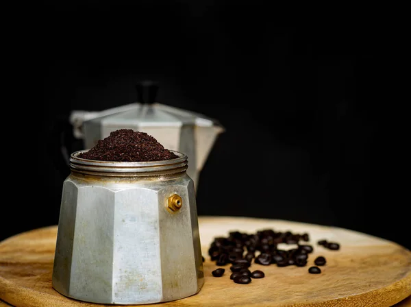 An image coffee ground in moka pot is a coffee maker is a beverage for break morning on the dark background.