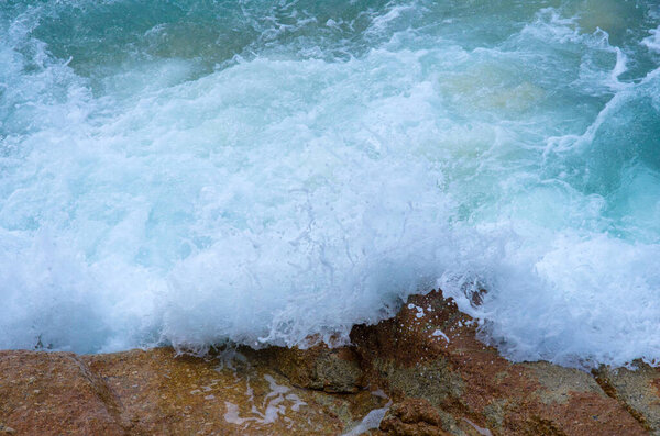 Брызги воды. Кристально чистая морская вода бьется о скалы и скалы. Волны и морская пена.