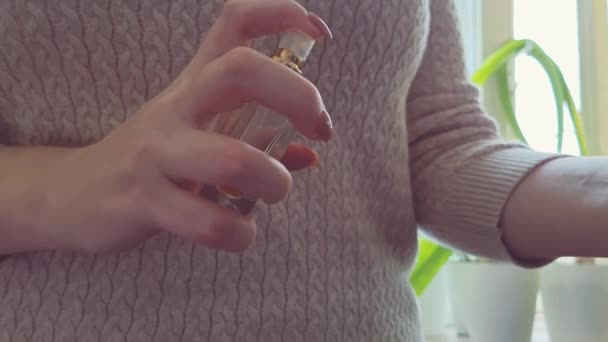 Žena si rozstřikuje parfém na zápěstí. Koncept sebepéče. Detailní záběr rukou držících láhev eau de parfum. — Stock video