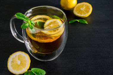 Koyu arkaplanda limonlu ve naneli bitki çayı. Rahatlamak ve ferahlamak için lezzetli bir içecek.