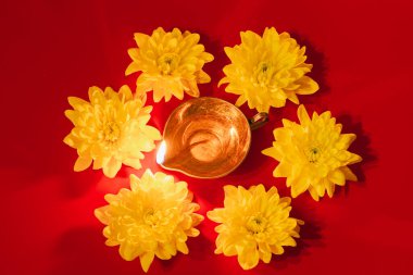 Diwali Hint Işık Festivali. Kırmızı arka planda Diya yağı lambası ve sarı çiçekler. Geleneksel Hindu kutlaması. Boşluğu kopyala.
