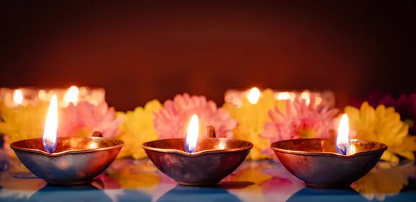 Glücklicher Diwali. Traditionelle Symbole des indischen Lichterfestes. Brennende Diya-Öllampen und Blumen auf rotem Hintergrund. — Stockfoto
