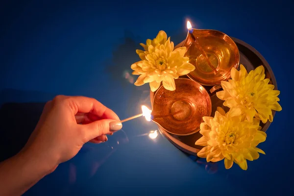 幸せなディワリ 女性は伝統的なオイルランプを点灯します 光の祭りを祝う 青地にダイヤと黄色い花を咲かせます — ストック写真