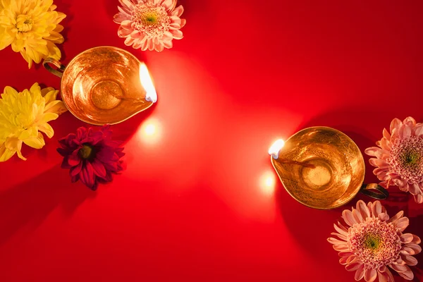 Stock image Happy Diwali. Traditional Hindu celebration. Diya oil lamps and flowers on red background. Religious holiday of light. Copy space.