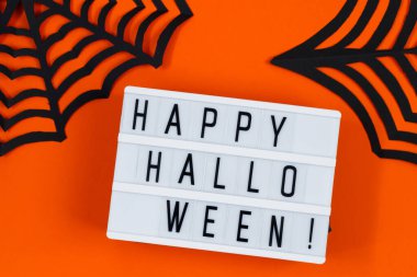 Cadılar Bayramı konsepti Turuncu arka planda şenlik dekorasyonları. Asgari tasarım.