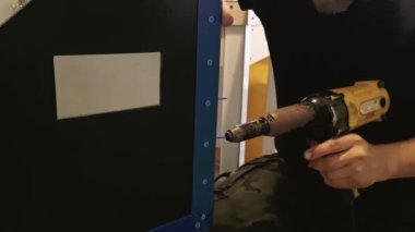 Erkek tamirci, perçin tabancasıyla çalışıyor. Ellerinde elektrikli perçin makinesi var. Metal için kör perçinler. Yavaş çekim.