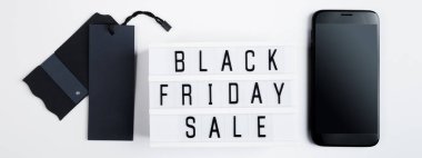 Kara Cuma indirimi. Beyaz arka planda etiket ve cep telefonu. Çevrimiçi alışveriş kavramı.