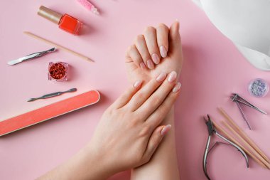 Güzellik salonunda çivi bakım prosedürü. Pembe arka planda kadın eli ve manikür aletleri. Spa vücut bakımını kabul et.