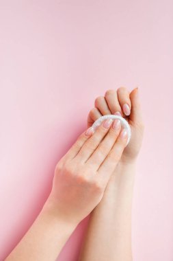 El bakımı konsepti. Genç bir kadın pembe arka planda oje sürüyor. Metin için yer.