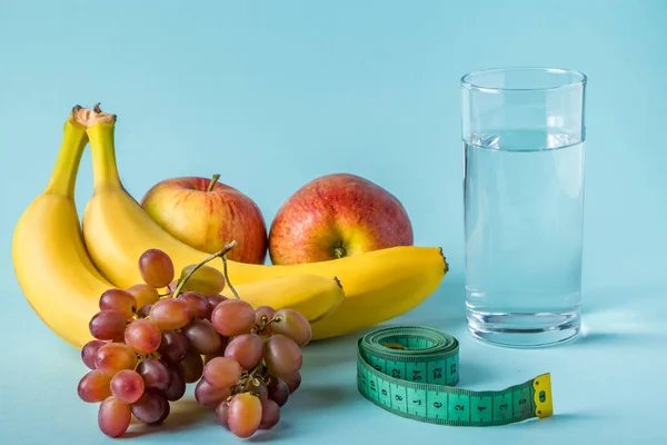 Owoce, szklanka wody i taśma pomiarowa na niebieskim tle. Koncepcja diety i właściwego odżywiania. — Zdjęcie stockowe