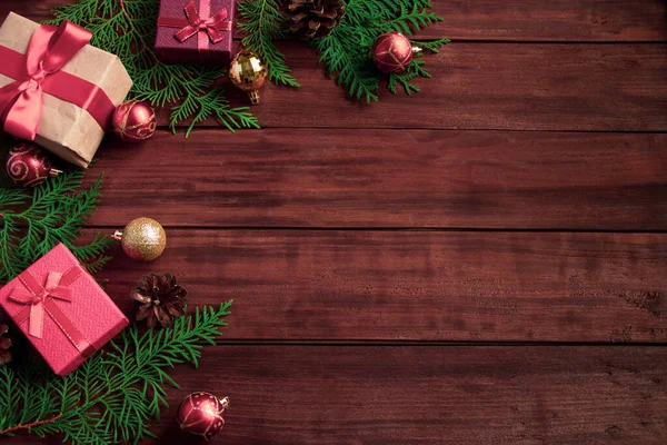 Красиві подарункові коробки, ялинкові гілки та різдвяні кульки на дерев'яному фоні . — стокове фото