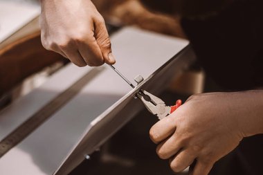 Mobilya montajcısı tornavidayla çalışır. Erkek işçi metal mandal takıyor. Eller tamir aletini tutsun. Küçük işletme desteği. İnşaat atölyesinde yaşam tarzı.