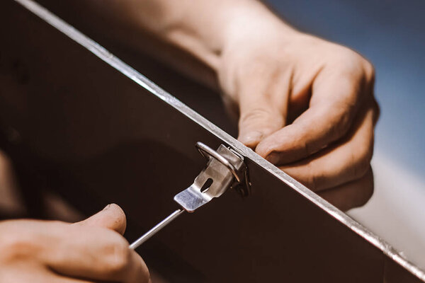 Механик сборщика мебели работает с отверткой. Рабочий мужчина устанавливает металлическую защелку. Руки держат инструмент для ремонта. Поддержка малого бизнеса. Стиль жизни в строительном цехе.