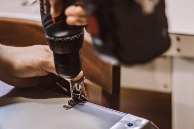 Erkek tamirci elektrikli matkapla çalışıyor. İşçi delik açar. Mobilya montajcısı metal mandal takıyor. El yapımı, el yapımı..