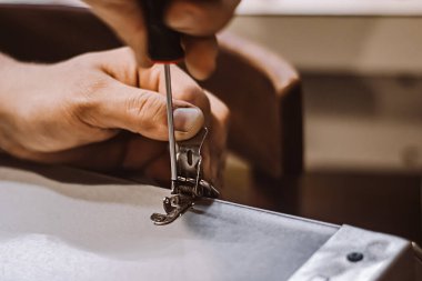 Mobilya montajcısı tornavidayla çalışır. Erkek işçi metal mandal takıyor. Eller tamir aletini tutsun. Küçük işletme desteği. İnşaat atölyesinde yaşam tarzı.