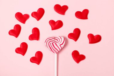 Lolipop and red hearts on pink background. Valentine's day concept.