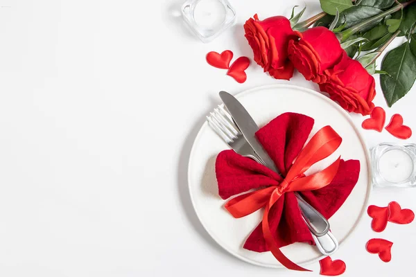 バレンタインデーのテーブルセッティング 白い背景に赤いバラとカトラリー ストックフォト