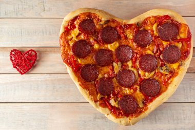 Ahşap arka planda kalp şeklinde pepperoni pizza. Sevgililer günü hediyesi. Aşıklar için şölen yemeği. Fast food. Restoran menüsü için tasarım