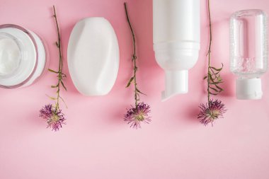 Pembe arka planda kozmetik ürünler. Beyaz krem ve losyon şişeleri. Spa aksesuarları, vücut bakımı. Refah kavramı.