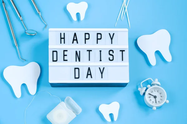 幸せな国際歯科医の日 紙は青の背景に歯と歯の道具のモックアップをカットしました 歯科医療の概念 プロの休日の挨拶カード スペースのコピー ロイヤリティフリーのストック画像