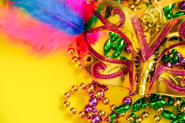 Sarı arka planda karnaval maskesi ve boncuklar. Mardi Gras konsepti. Şişman Salı sembolü. Tatil dekorasyonları kapanıyor..