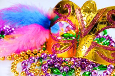 Altın karnaval maskesi ve beyaz arka planda renkli boncuklar. Mardi Gras ya da Fat Tuesday 'in yakın çekim sembolü. Altın, yeşil ve mor tatil süslemeleri..