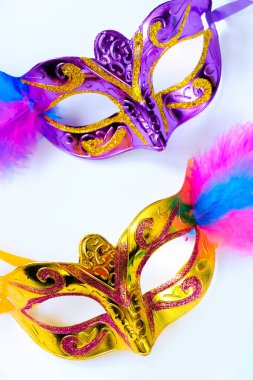 Tüylü iki karnaval maskesi ve beyaz arka planda çok renkli boncuklar. Mardi Gras veya Fat Tuesday sembolü. Geleneksel tatil için tebrik kartı. Dikey fotoğraf.