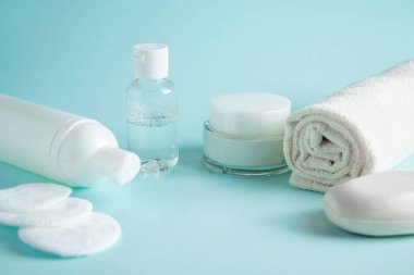 Mavi arka planda kozmetik ürünleri ve spa aksesuarları. Krema, sabun ve havlu. Cilt bakımı, sağlık konsepti. Boşluğu kopyala.