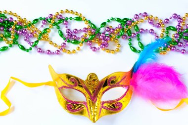 Tüylü karnaval maskesi ve beyaz arka planda renkli boncuklar. Mardi Gras veya Fat Tuesday sembolü. Geleneksel tatil için şenlik süslemeleri.