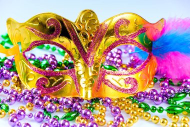 Altın karnaval maskesi ve renkli boncuklar. Mardi Gras veya Fat Tuesday sembolü. Geleneksel festival kavramı. Altın, yeşil ve mor tatil süslemeleri..