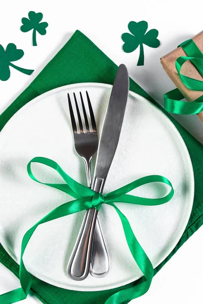 Plate and cutlery on a green napkin. Festive table setting for St. Patricks Day. Shamrock symbol of luck. — Stock Photo, Image