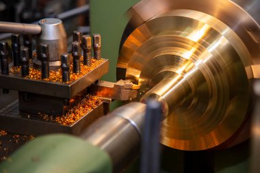 Torna makinesi pirinç şaft parçalarını torna araçlarıyla kesiyor. Makineyi döndürerek metal işleme süreci.