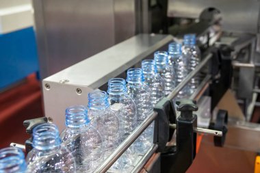 İçme suyu fabrikasındaki işlemleri tamamlamak için konveyör bandındaki boş PET şişeleri. Plastik şişe üretim sürecinin yüksek teknolojisi..