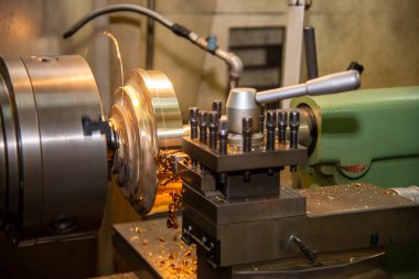 Torna makinesi pirinç şaft parçalarını torna araçlarıyla kesiyor. Makineyi döndürerek metal işleme süreci.