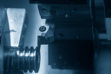 CNC torna makinesi kanalı aydınlatma efektiyle metal makara parçalarını kesiyor. CNC dönüşüm makinesinin yüksek teknolojili otomotiv parçaları üretim süreci .