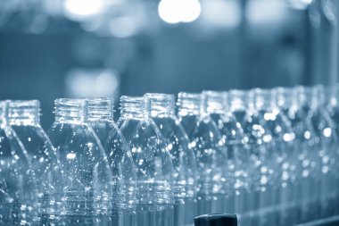 İçme suyu fabrikasındaki işlemleri tamamlamak için konveyör bandındaki boş PET şişeleri. Plastik şişe üretim sürecinin yüksek teknolojisi..