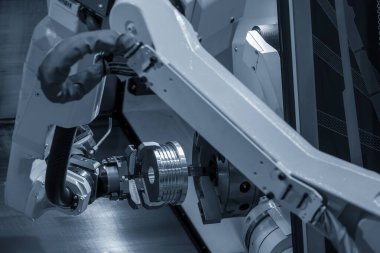 CNC torna makinesinin metal parçalarını tutan otomatik robot kolu. Dönüşüm makinesinde robotik sistem tarafından yüksek teknoloji materyal işleme süreci. 